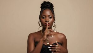 Draw me a portrait using this close-up image of a young BLACK AFRICAN Kenyan woman with BLACK hair and dark African skin, styled in a high, messy bun. A few loose strands frame her face. She has striking makeup, with sharply defined black cat-eye eyeliner, well-defined eyebrows, red lips, brown eyeshadow, subtle blush, and highlighter. She's making a 'shushing' gesture with the index finger of her right hand to her lips. She's wearing a strapless black corset top, revealing her shoulders. Many gold accessories adorn her neck and hands: several necklaces of varying lengths, some with pendants, large gold hoop earrings, and rings on her fingers. Her nails are long and white. The background is a plain, neutral brown, creating a contrast with her gold jewelry and skin tone. Keep facial features as clear as possible